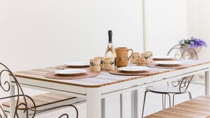 Una mesa de comedor dispuesta con platos, tazas y una botella, rodeada de sillas.