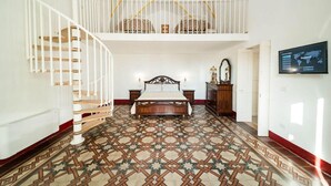 Un dormitorio con una cama grande, una escalera, un candelabro y un televisor en la pared.