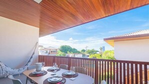 An outdoor patio with a wooden ceiling, a dining table set for four, and a hammock.