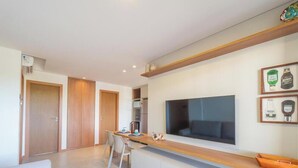 A modern kitchen with a large TV, wooden cabinets, and a dining area with chairs.