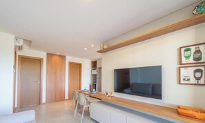 Cozinha moderna com uma televisão grande, armários de madeira e uma área de refeições com cadeiras.