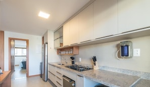 Uma cozinha moderna com fogão a gás, eletrodomésticos de aço inoxidável e forno embutido.