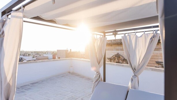 Eine Dachterrasse mit Blick auf die Stadt, einer Pergola und einem Tisch mit Stühlen.