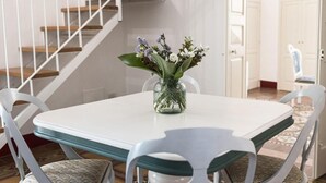 Ein Essbereich mit einem weißen Tisch, Stühlen und einer Blumenvase.