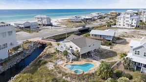 Un quartier résidentiel en bord de mer, avec des maisons, une piscine et une vue sur la plage.