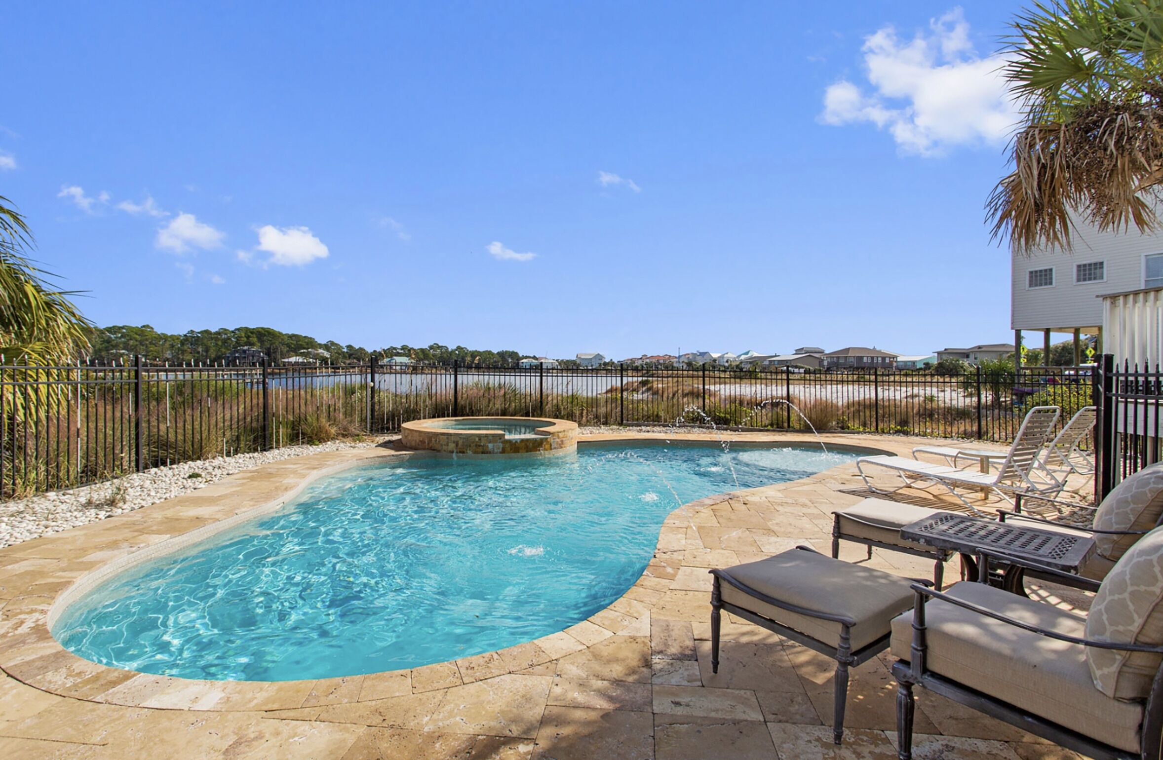 A swimming pool with a hot tub, lounge chairs, and a view of the beach.