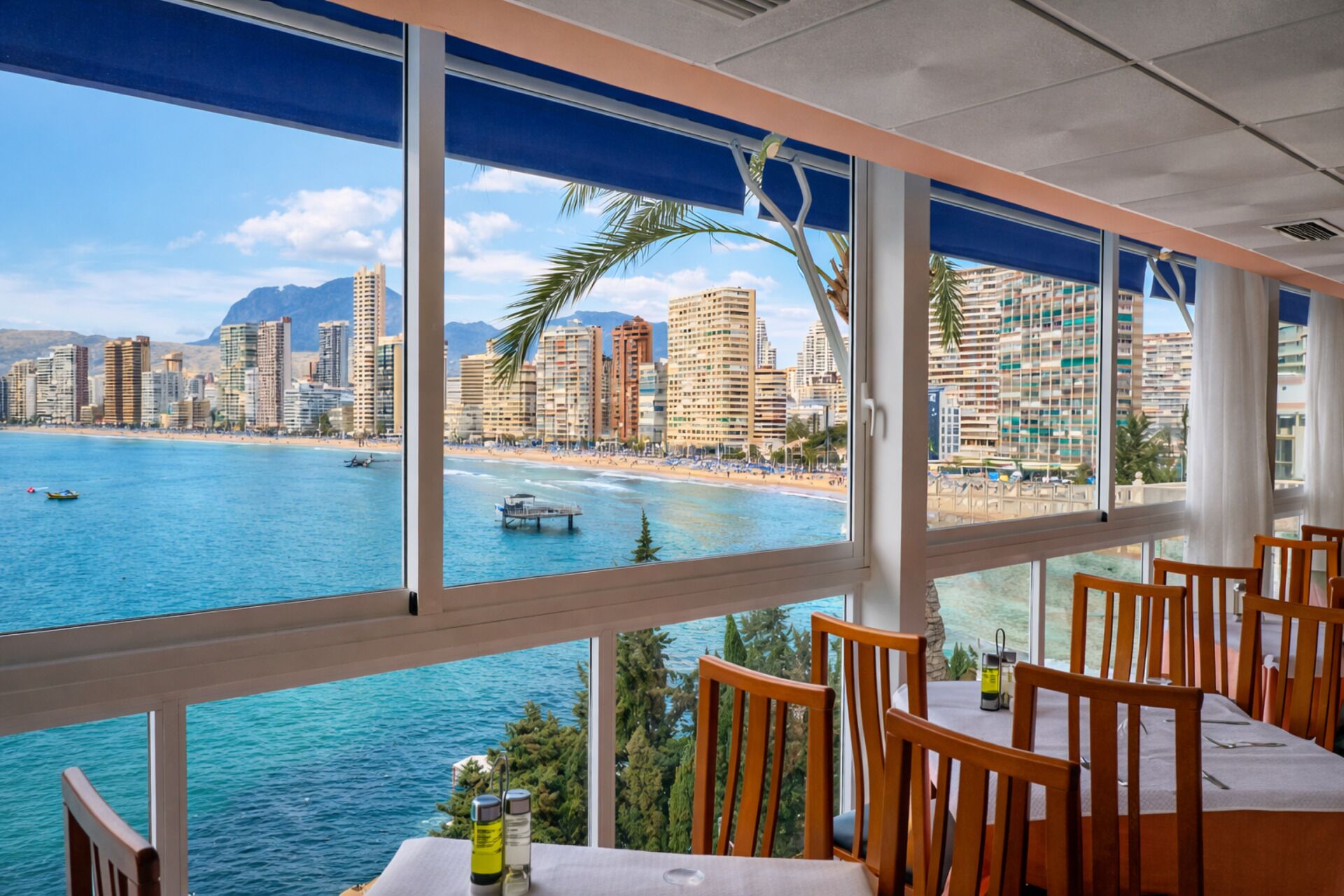 A dining area with a view of a coastal cityscape, including a beach and high-rise buildings.