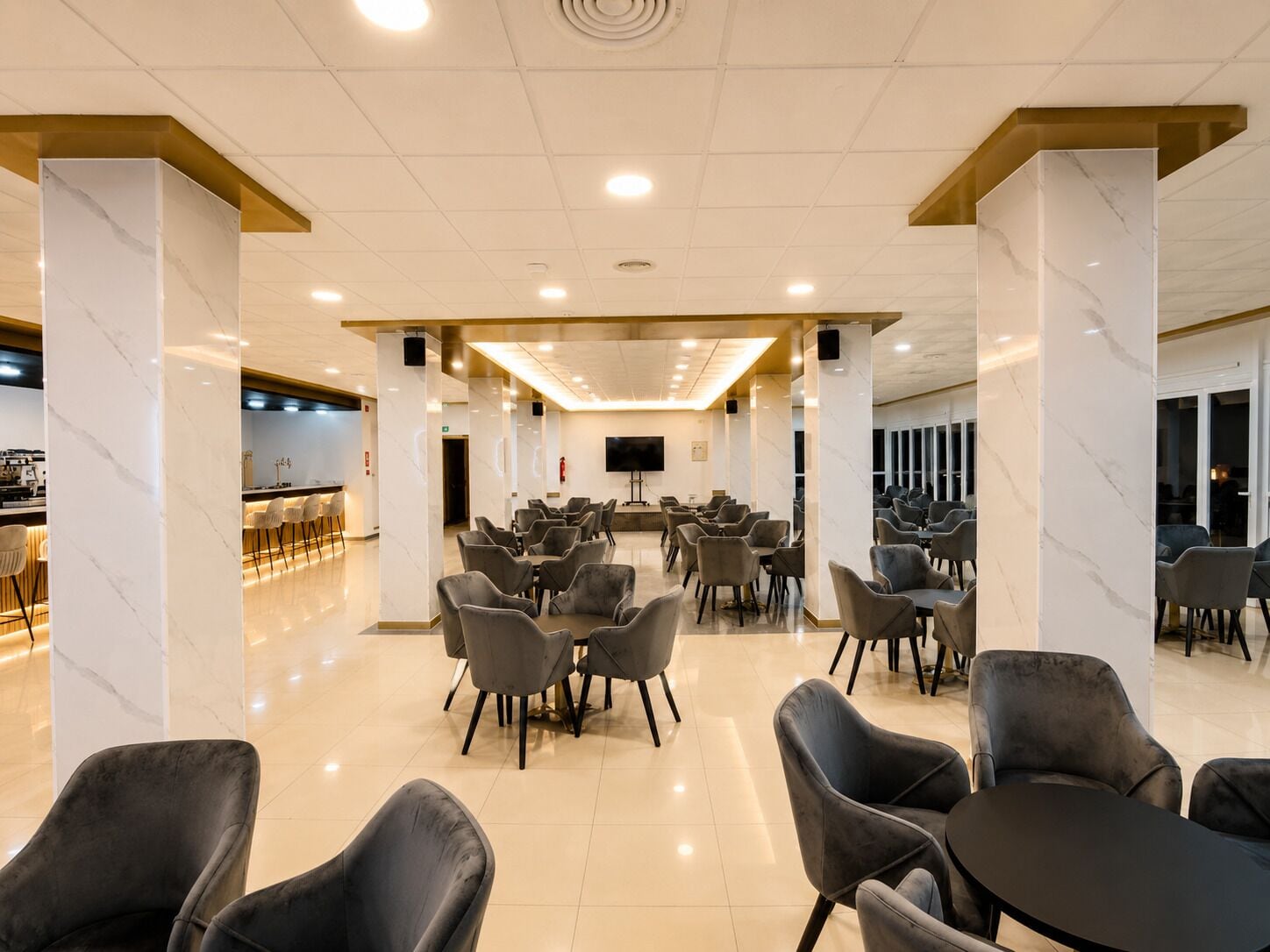Een ruime vergaderzaal met marmeren zuilen, een bar en een flatscreen-tv.