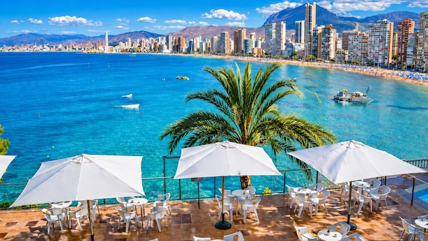 Paisagem costeira com vista nítida do mar, uma praia e o horizonte da cidade.