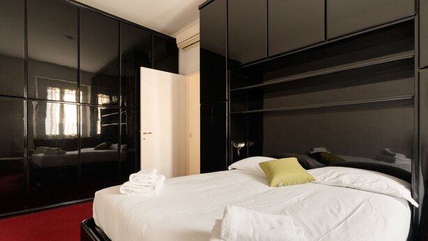 A hotel room with a large bed, a wardrobe, and a mirror. - GuestHost - Cozy apartment of approximately 55 m2, able to accommodate up to 4 people, located on the first floor of a building with lift (NOT suitable for people in wheelchairs).The property is located in the Risorgimento district, in a residential area (Milan)