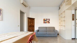 A living room with a sofa, a dining table with chairs, and a cabinet. - GuestHost - Cozy apartment of approximately 55 m2, able to accommodate up to 4 people, located on the first floor of a building with lift (NOT suitable for people in wheelchairs).The property is located in the Risorgimento district, in a residential area (Milan)