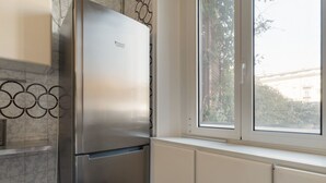 A kitchen with a stainless steel refrigerator, a window with a view of buildings, and a decorative wall pattern. - GuestHost - Cozy apartment of approximately 55 m2, able to accommodate up to 4 people, located on the first floor of a building with lift (NOT suitable for people in wheelchairs).The property is located in the Risorgimento district, in a residential area (Milan)