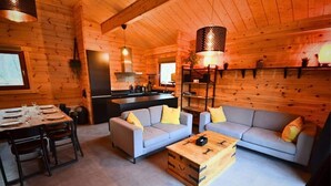 Een vakantiehuisje van binnen, met een eethoek, twee banken, een salontafel en een keukenhoek.