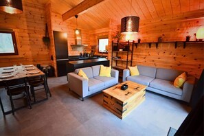 A log cabin interior with a dining area, two sofas, a coffee table, and a kitchen area. - Ardennes Chalet With Balcony, Sauna (Viroinval)
