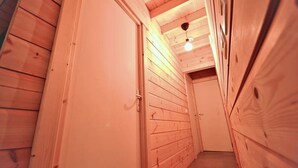 Een smalle houten gang met een deur aan de linkerkant en een lamp aan het plafond.