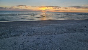 Une plage avec un coucher de soleil sur l’océan.