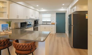 A modern kitchen with white cabinets, stainless steel appliances, and a central island. - Waterfront Modern Condo - 2BR/2BA - Pool - Intracoastal Views - Beach Access (Indian Shores)