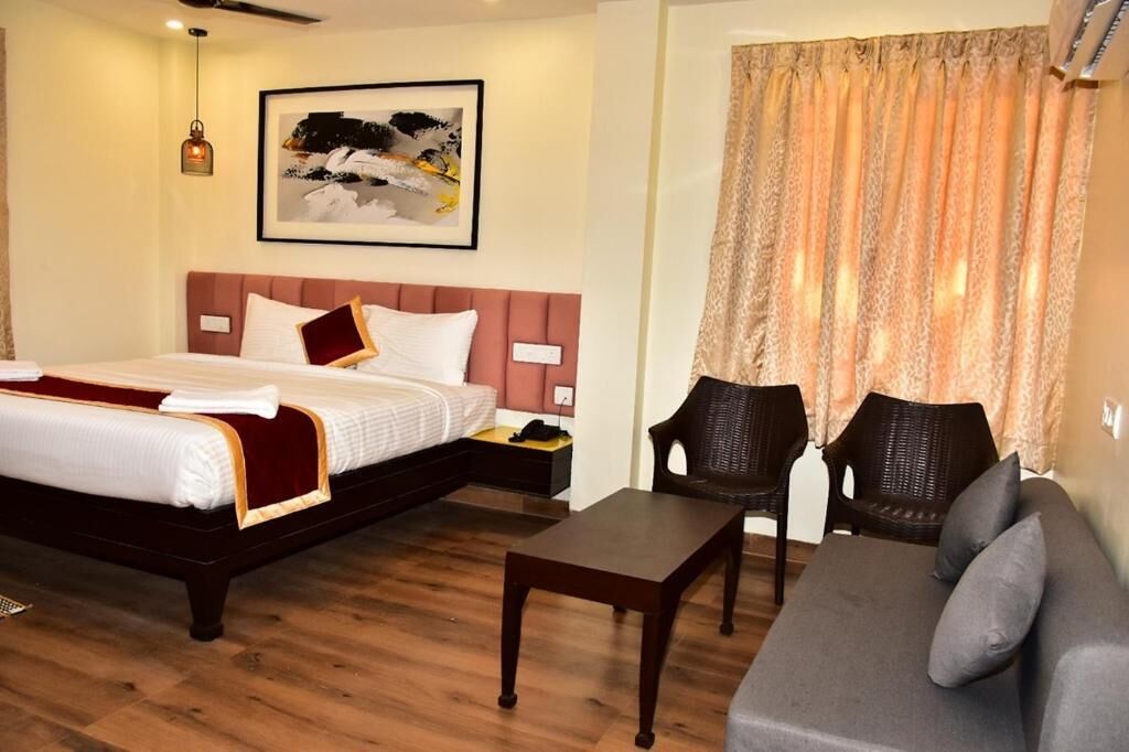 A hotel room with a bed, a sofa, a small table, and a chair.