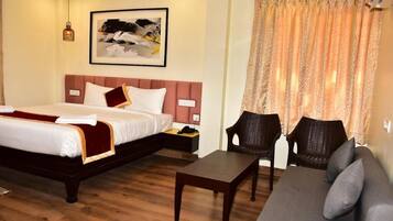 A hotel room with a bed, a sofa, a small table, and a chair.