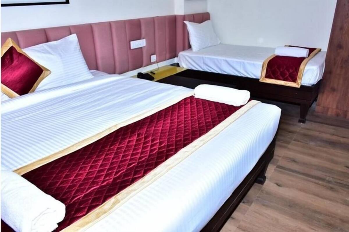 Ein Hotelzimmer mit zwei Betten, eines mit einer roten gesteppten Matratze und das andere mit einer weißen Matratze.