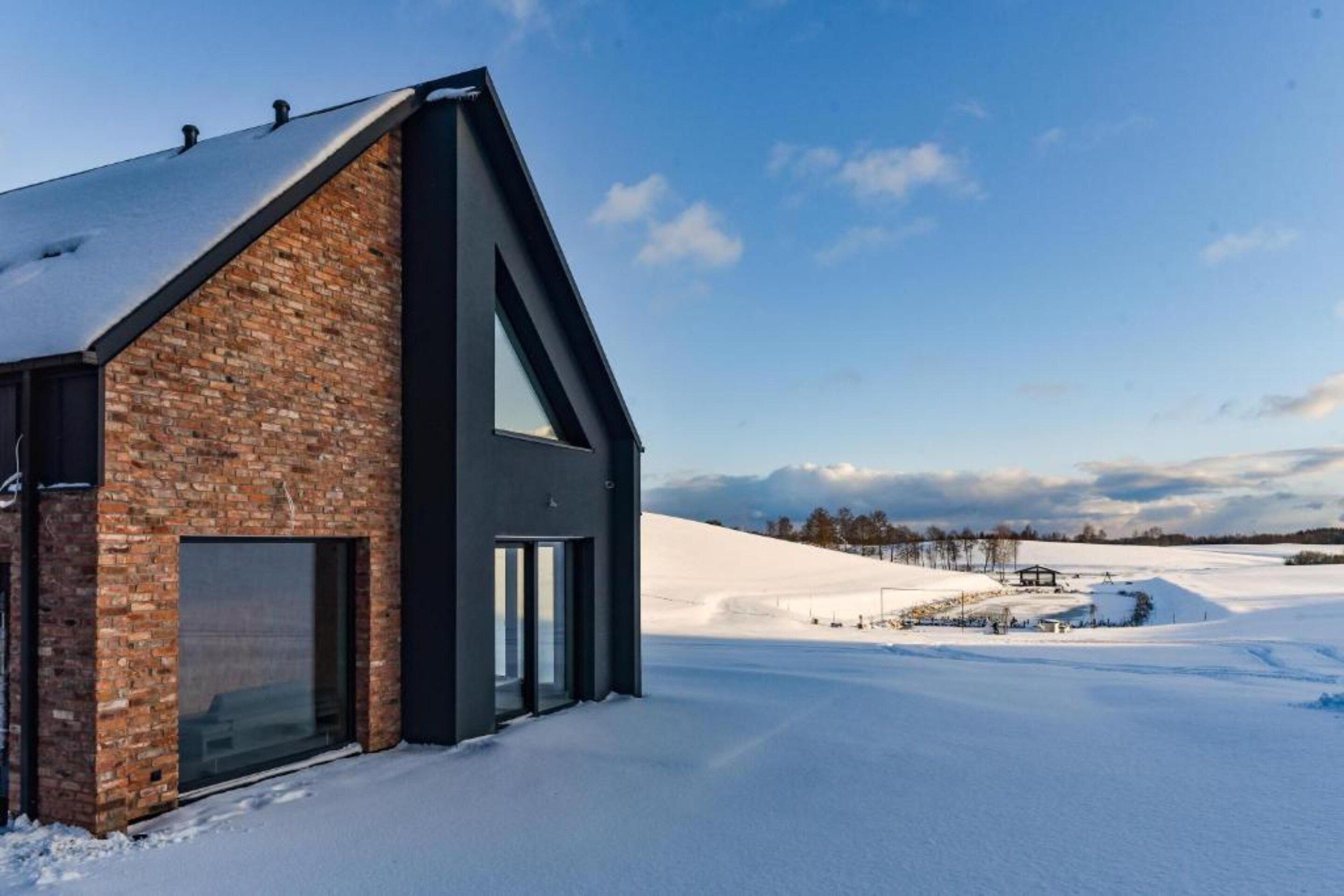 A modern building with a brick facade and large windows, set against a snowy landscape.