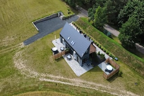 A modern house with a flat roof, a paved driveway, and a well-maintained lawn. - Holiday Home, Bedroom With Bathtub, Jacuzzi (Koscierzyna)