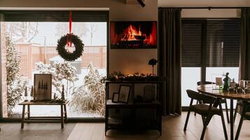 A cozy living room with a fireplace, a dining area, and a view of a snowy yard.