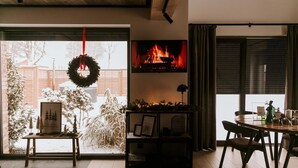 A cozy living room with a fireplace, a dining table, and a view of a snowy outdoor area. - Holiday Home, Bedroom With Bathtub, Jacuzzi (Koscierzyna)