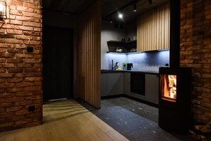 A modern kitchen with exposed brick walls, wooden cabinets, and a built-in stove. - Holiday Home, Bedroom With Bathtub, Jacuzzi (Koscierzyna)
