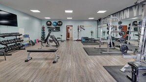Et fitnessrum med træningsudstyr, et vægmonteret tv og et spejl.
