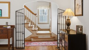 A staircase with a wooden finish, a black metal railing, a patterned rug, and a lamp on a cabinet. - MINNeSTAY* Como Classic (St. Paul)