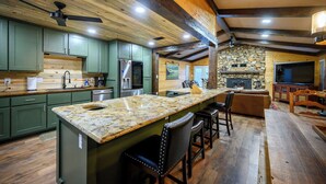 Una cocina con una isla grande, gabinetes verdes y una chimenea de piedra.
