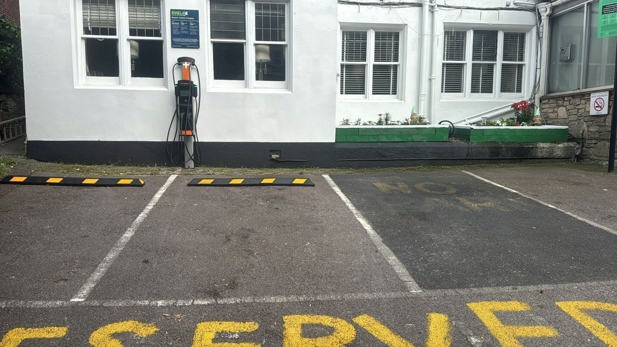 A building with a white exterior, a signboard, and a parking area with yellow markings.