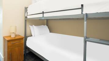 A bunk bed with a wooden nightstand and a lamp.