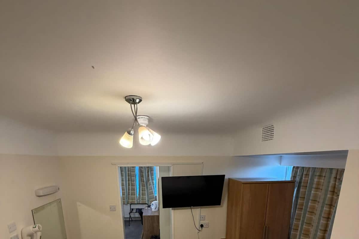 Une chambre d’hôtel avec deux lits, une télévision, une armoire et une salle de bain visible à travers une porte ouverte.