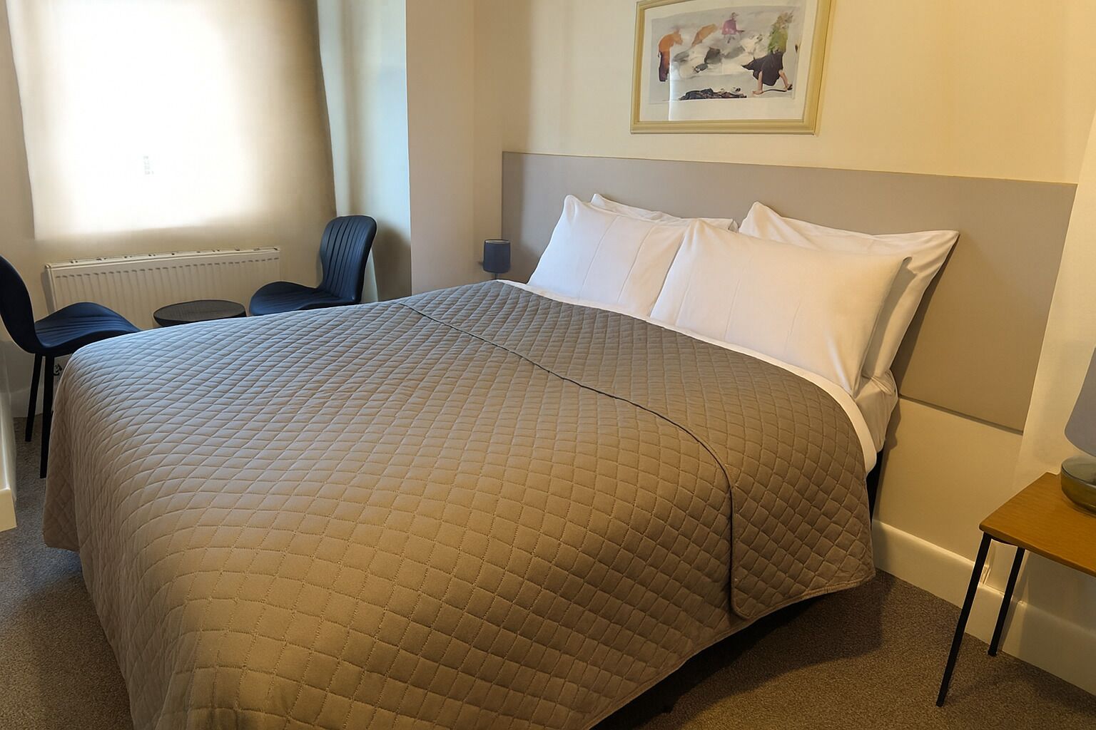 Una habitación de hotel con una cama grande, una silla, una mesita y un radiador.
