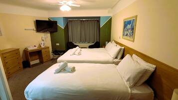 Habitación de hotel con dos camas, un escritorio, una silla, un televisor y un cuadro en la pared.