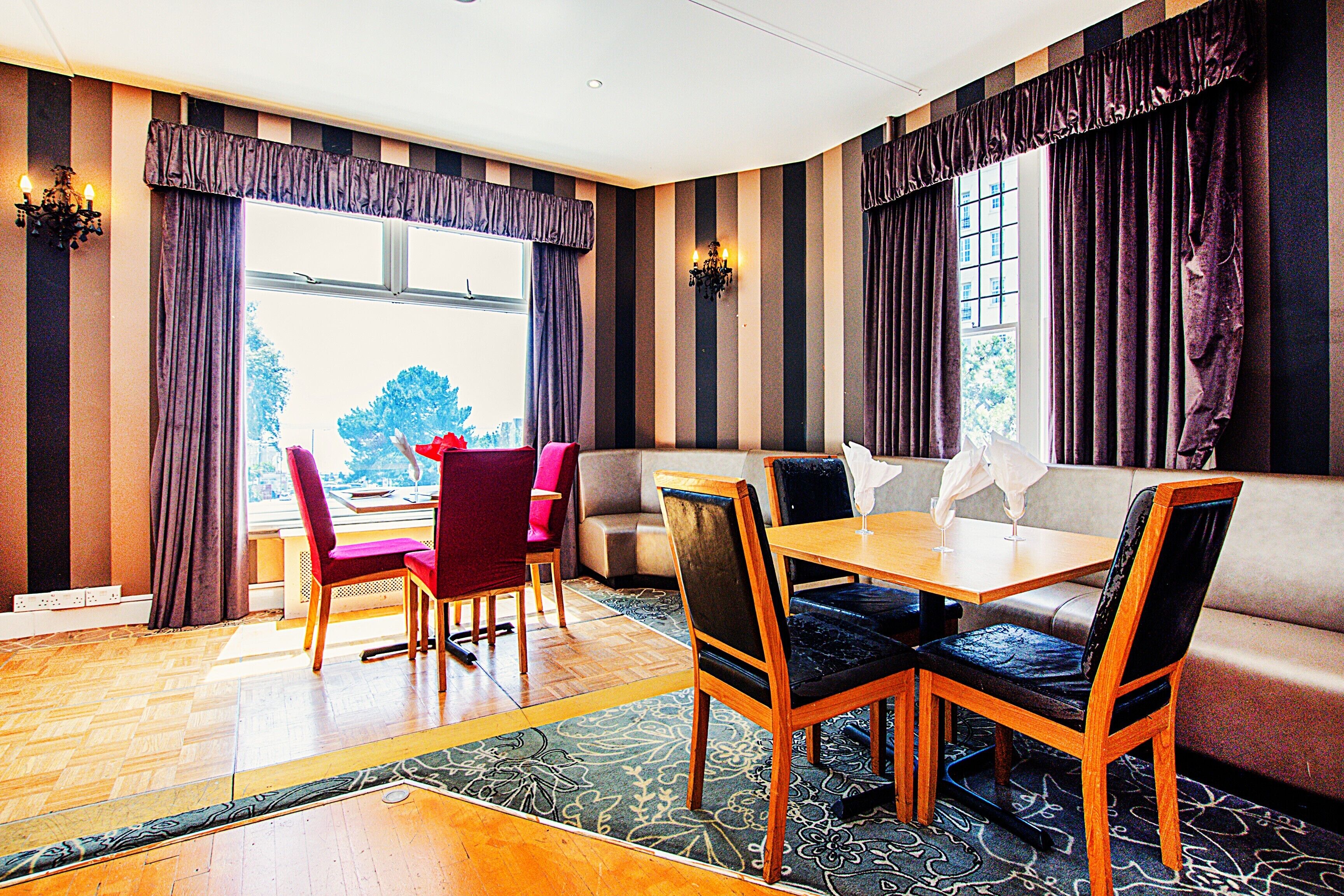 A hotel room with a dining area, a sofa, and a window with curtains.