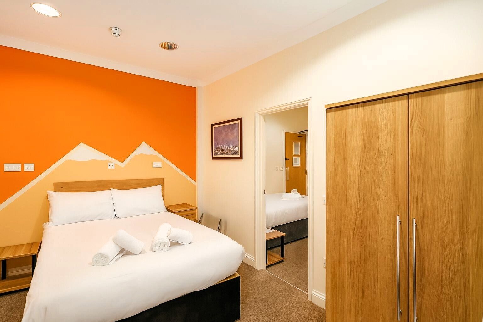 Una habitación de hotel con cama, un armario y una puerta que da a otra habitación.