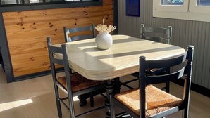 Un comedor con pared de acento de madera, una mesa redonda, sillas acolchadas y un florero con flores.