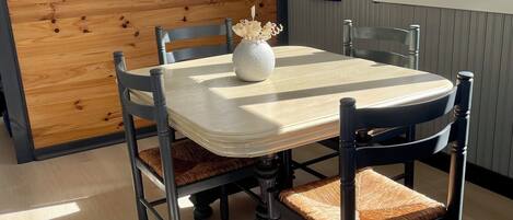 Un comedor con pared de acento de madera, una mesa redonda, sillas acolchadas y un florero con flores.