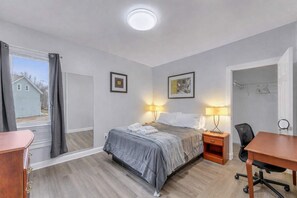 A bedroom with a bed, bedside lamps, a desk, and a chair.