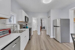 A modern kitchen with white cabinetry, a stainless steel refrigerator, and a red toaster.