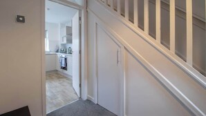 A hallway leading to a kitchen with a staircase. - Ash House 3 Bedroom in Cumbernauld (Glasgow)