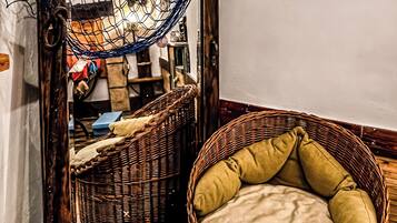A wicker chair with a cushion, a hammock, and wall decorations including a fish and a welcome sign.