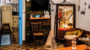 Et hyggeligt rum med en træstol, en fletsofa, et lille bord og en hængekøje.