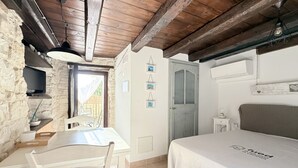 Une chambre à coucher avec un lit, un bureau, une chaise, une télévision et une porte.