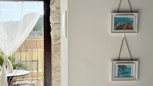 Une pièce avec une vue à travers une fenêtre, une porte et un cadre photo fixé au mur.