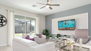 Ein modernes Wohnzimmer mit einem weißen Sofa, einem Glastisch und einem Deckenventilator.