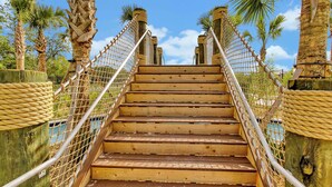 Eine Holztreppe mit Seilspindeln, umgeben von Palmen.